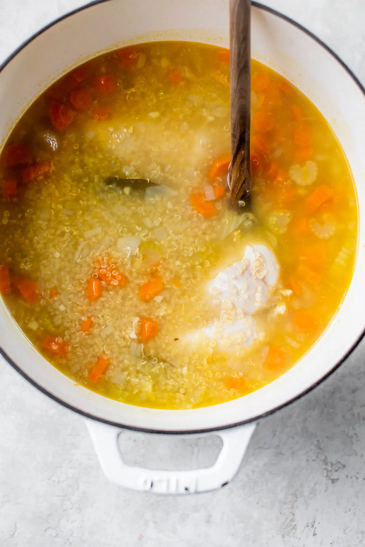 soup in a dutch oven with chicken breast and carrots