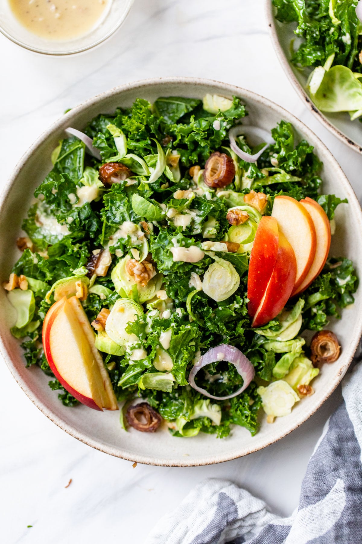 a bowl of kale salad with apples, brussels sprouts and shallots