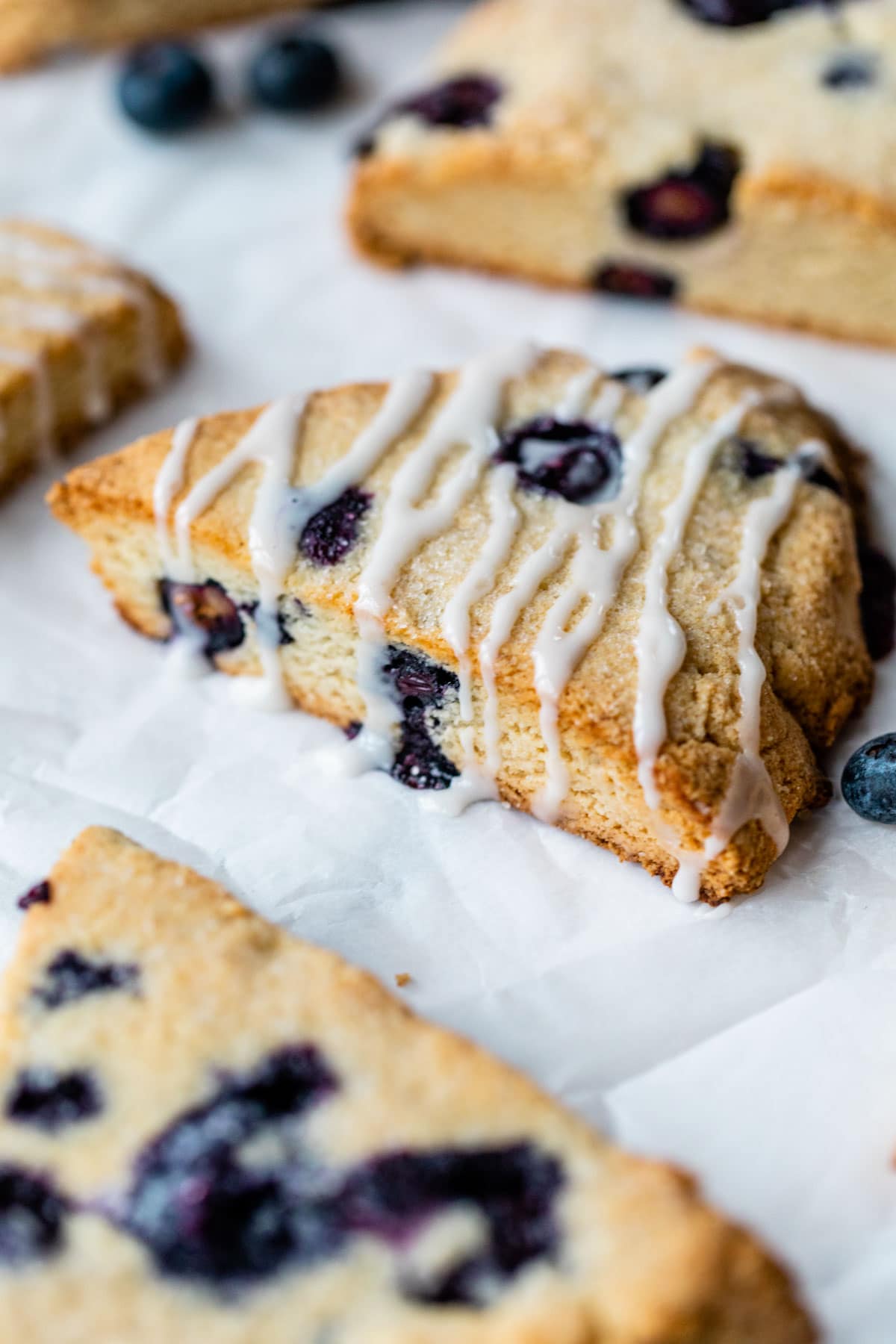 scones with blueberries and a glaze on parchment paper