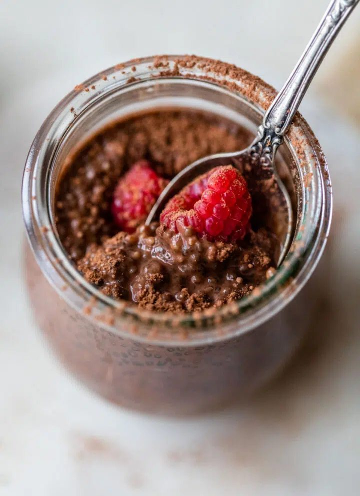 glass jar filled with chia pudding topped with raspberries
