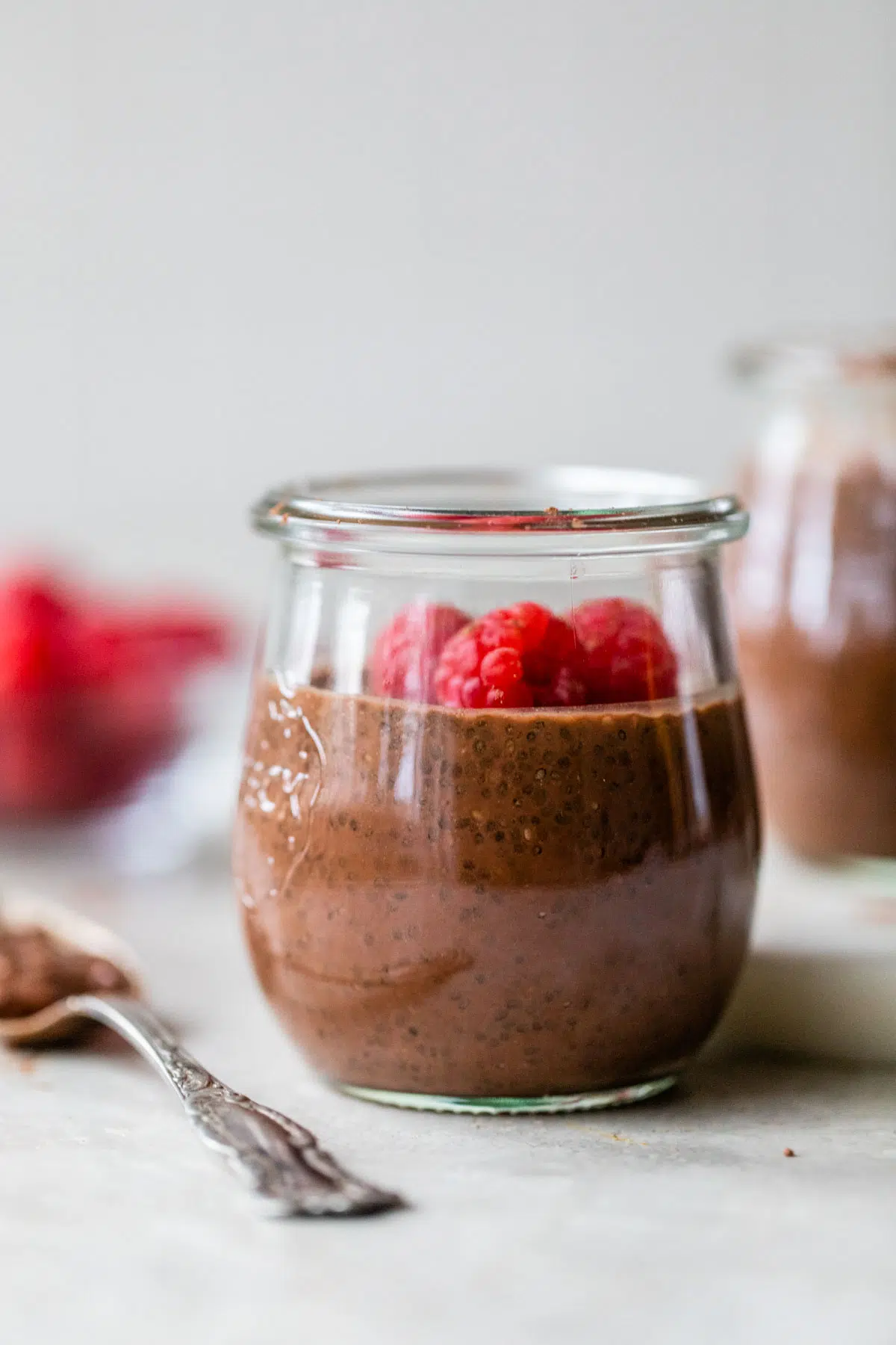 small jar filled with chocolate milk, chia seeds and raspberries