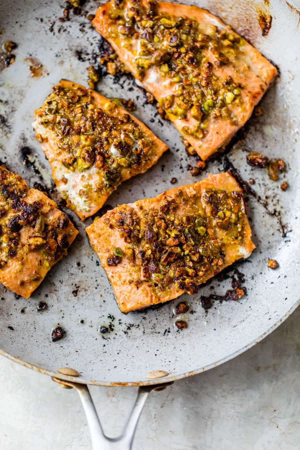 cooked salmon in a skillet topped with pistachios
