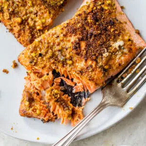 flakey salmon coated in pistachios on a white plate