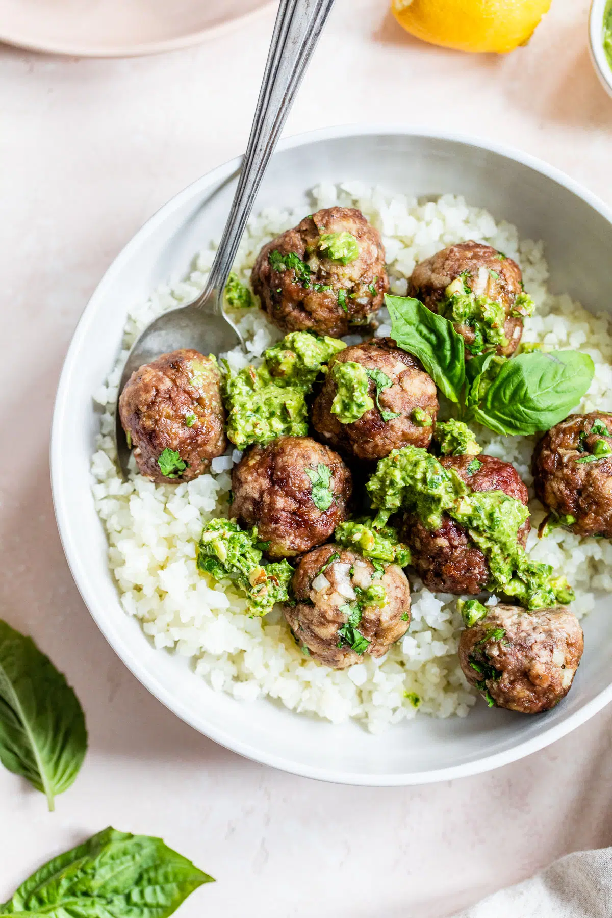 a bowl of cauliflower rice topped with meatballs and pesto