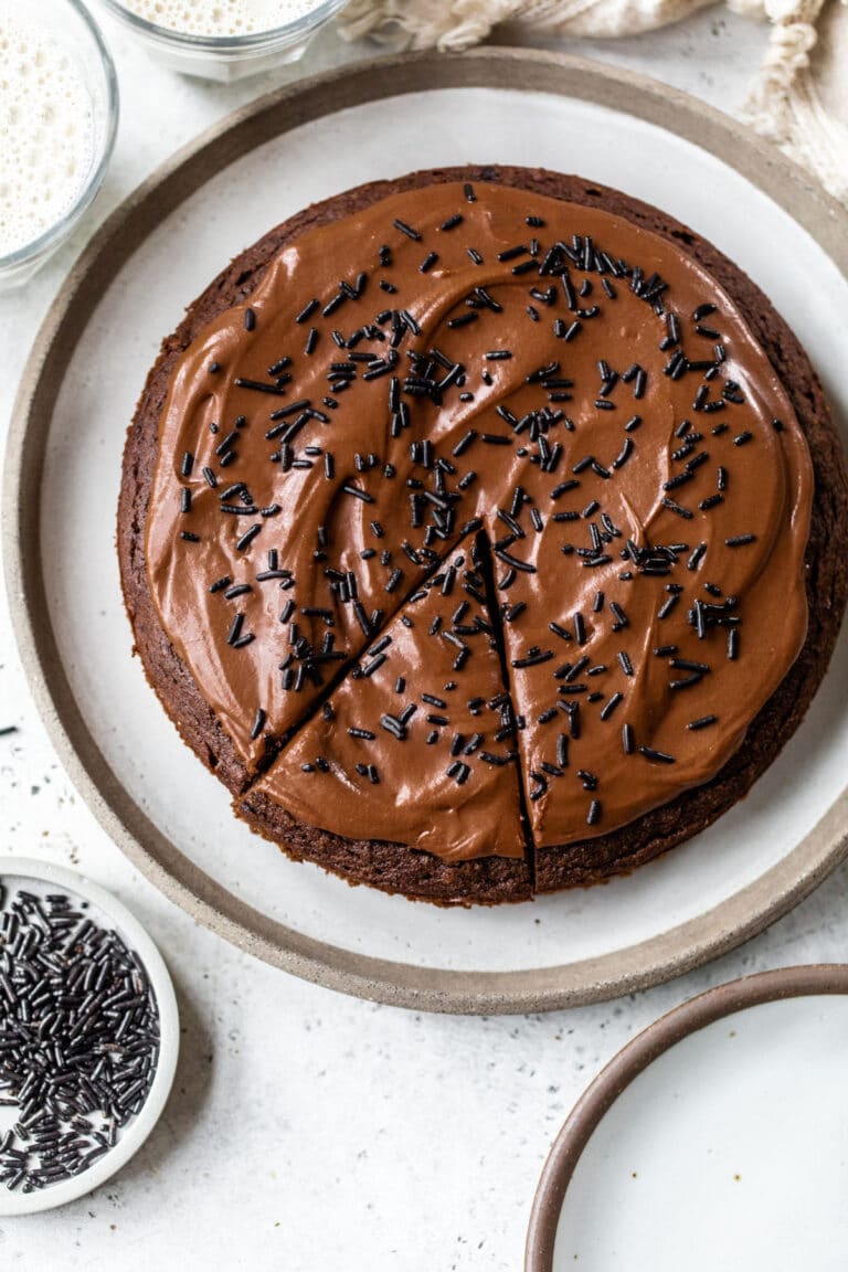 round chocolate cake on a plate topped with chocolate frosting and chocolate sprinkles