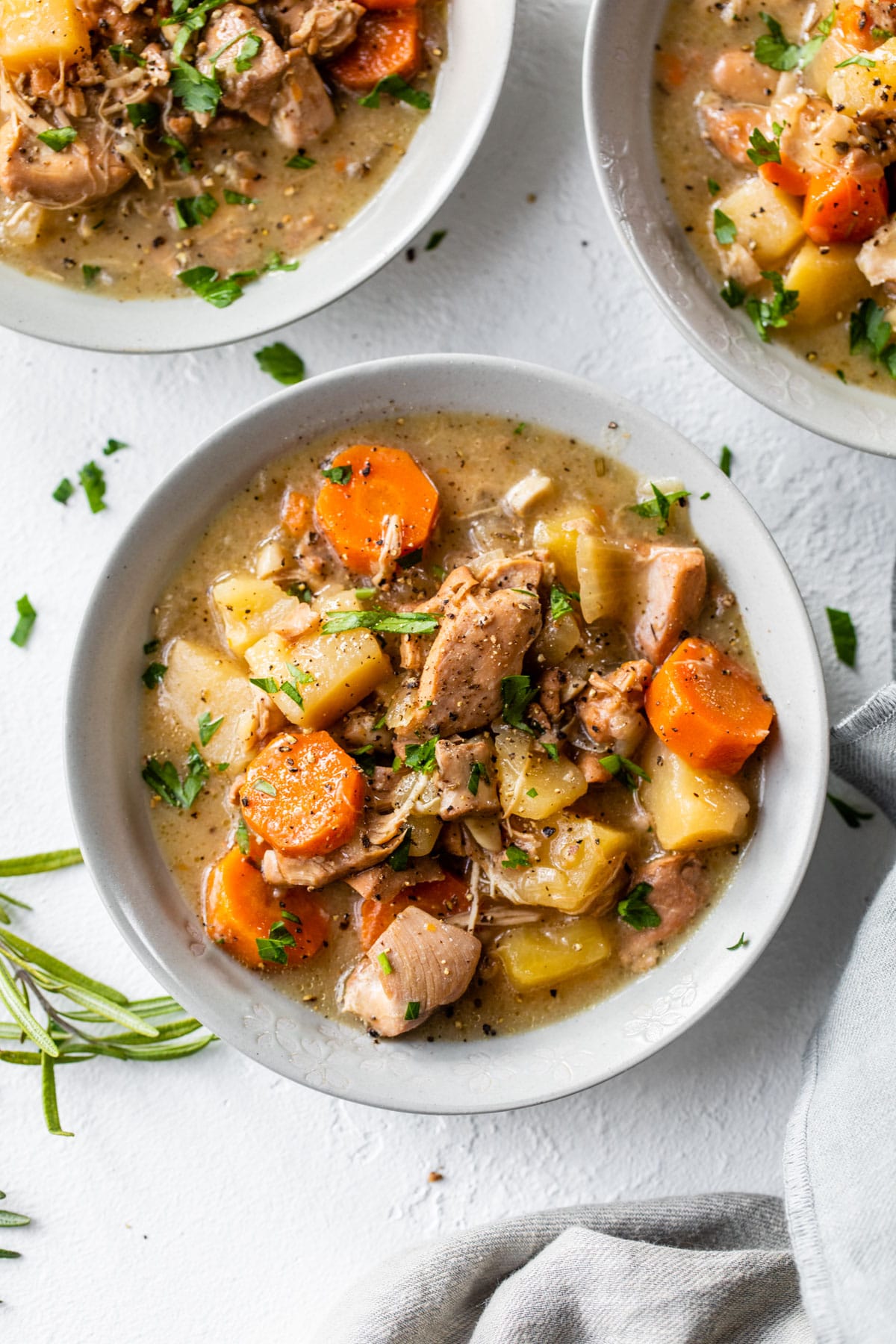 three bowls of stew with chicken, carrots and potatoes