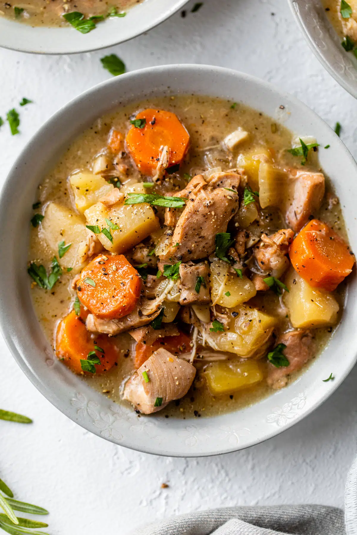 a bowl of stew with chicken, potatoes and carrots