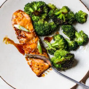 marinated salmon on a plate next to some broccoli