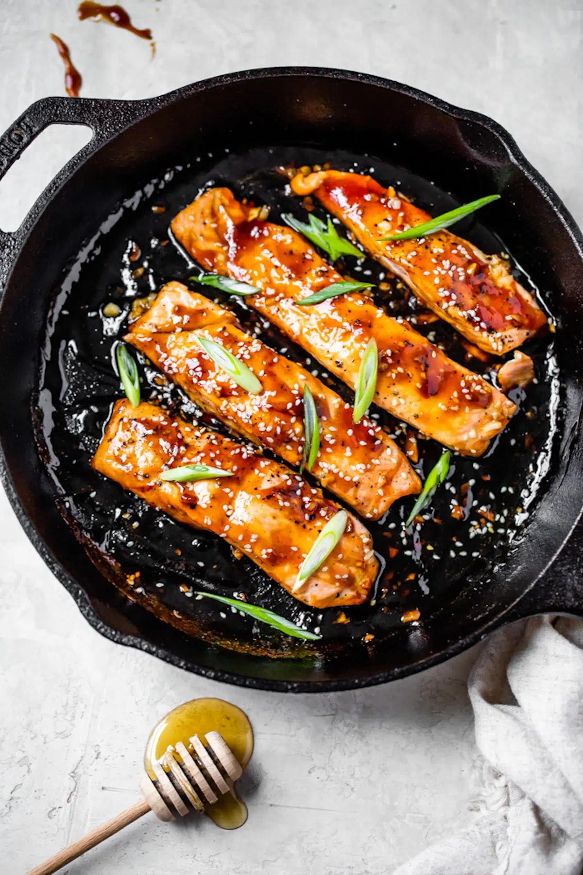 glazed salmon in a skillet topped with green onions