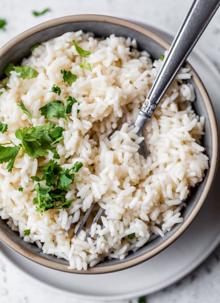 a bowl of coconut rice topped with cilantro and with a fork in the bowl