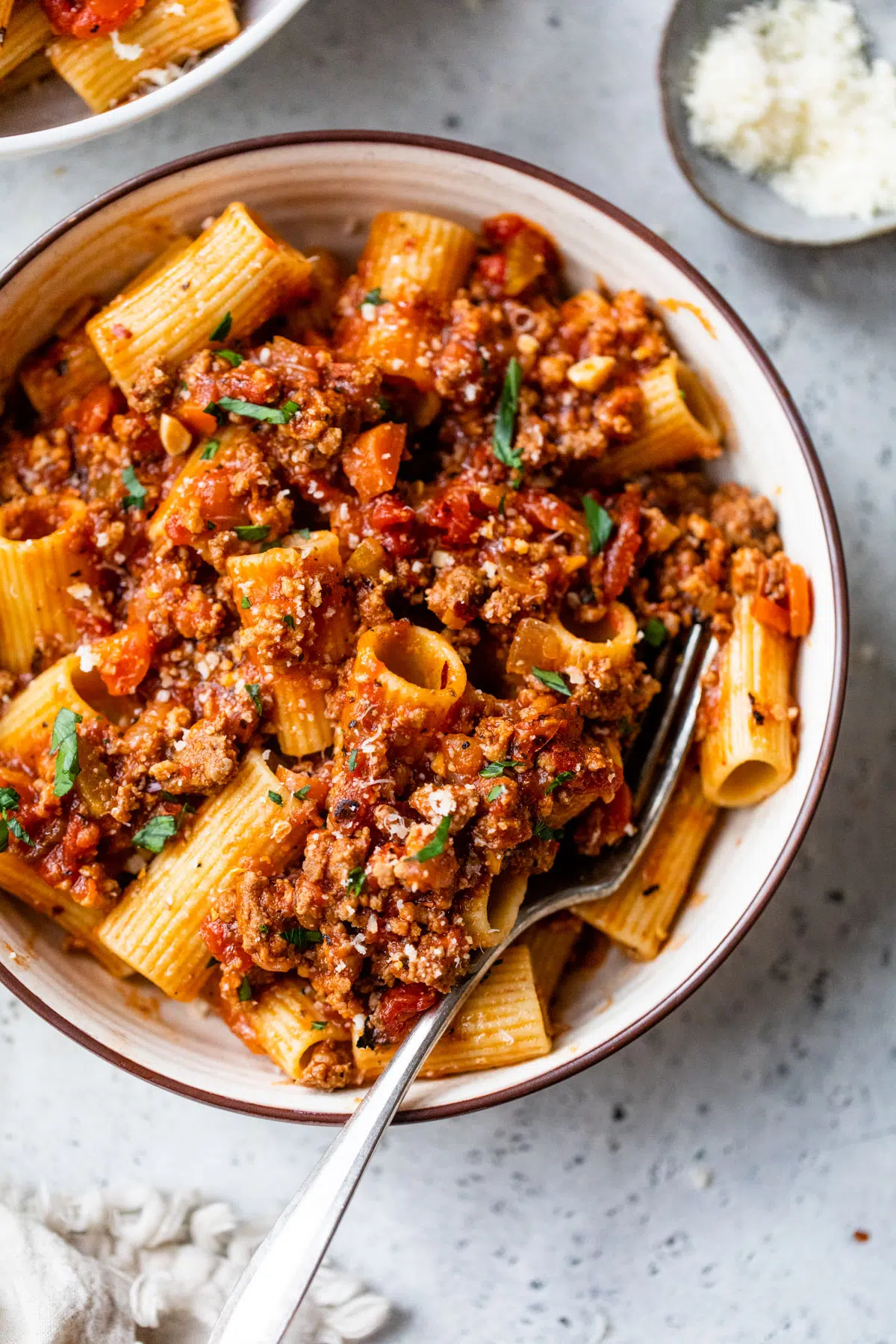 rigatoni in a bowl coated in bolognese sauce
