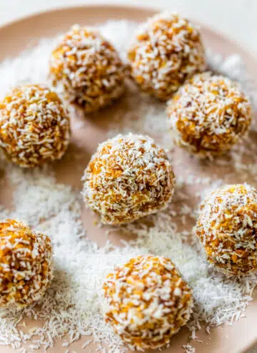 mango balls on a plate covered in shredded coconut