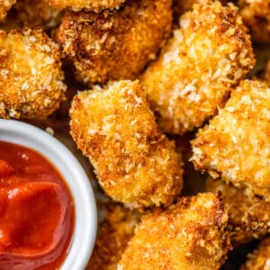 close up of chicken nuggets beside a small bowl of ketchup