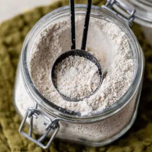 a glass jar with oat flour and a tablespoon measuring spoon in it