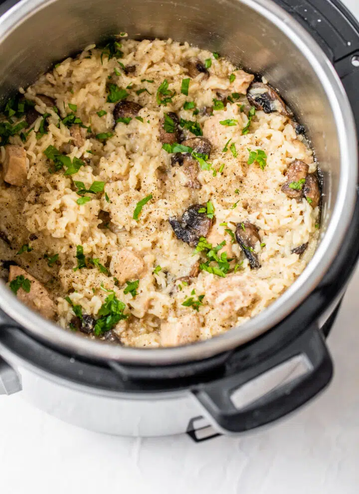 pressure cooker with rice, chicken, mushrooms, and fresh parsley