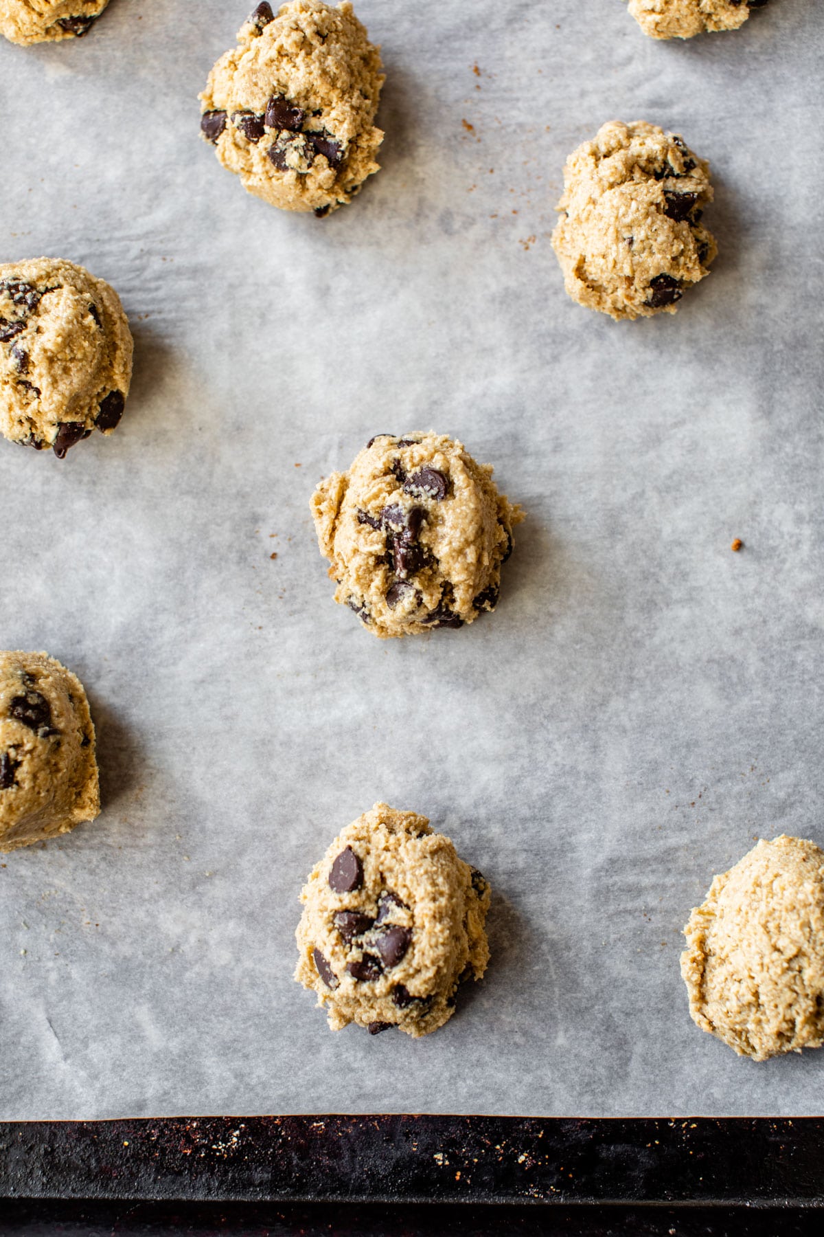raw cookie dough with chocolate chips on a parchment lined baking sheet