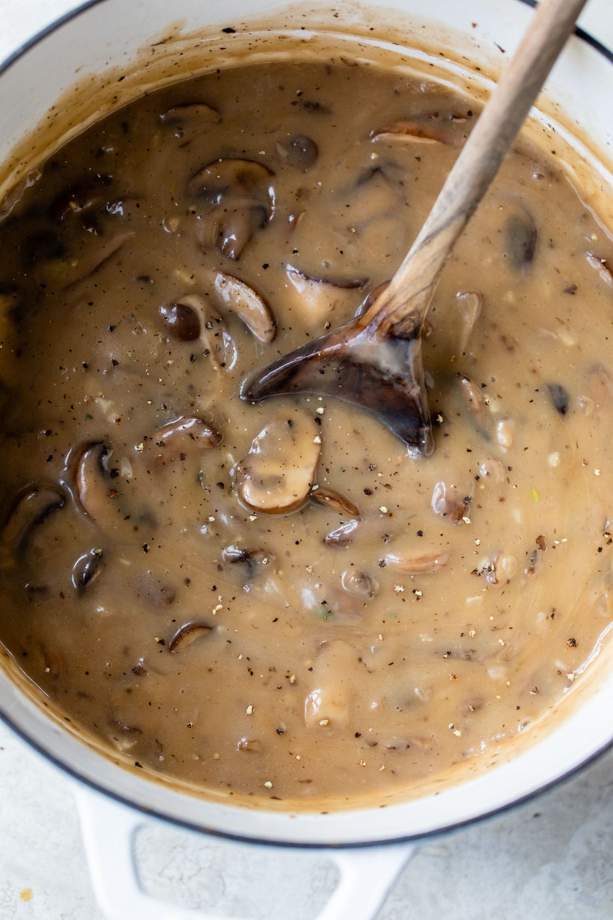 creamy mushroom soup in a dutch oven with a wooden spoon