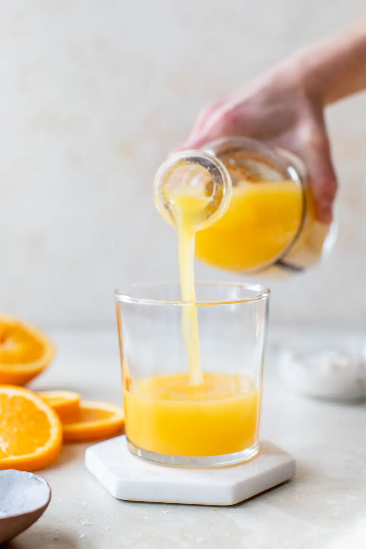 someone pouring orange juice from a bottle into a glass