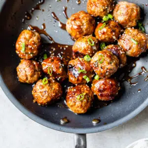 cooked meatballs in a skillet with an asian sauce