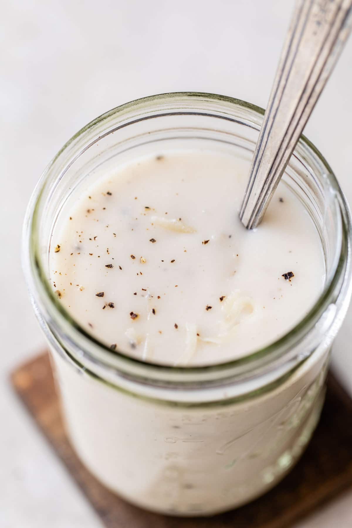 creamy white sauce in a glass jar sprinkled with black pepper