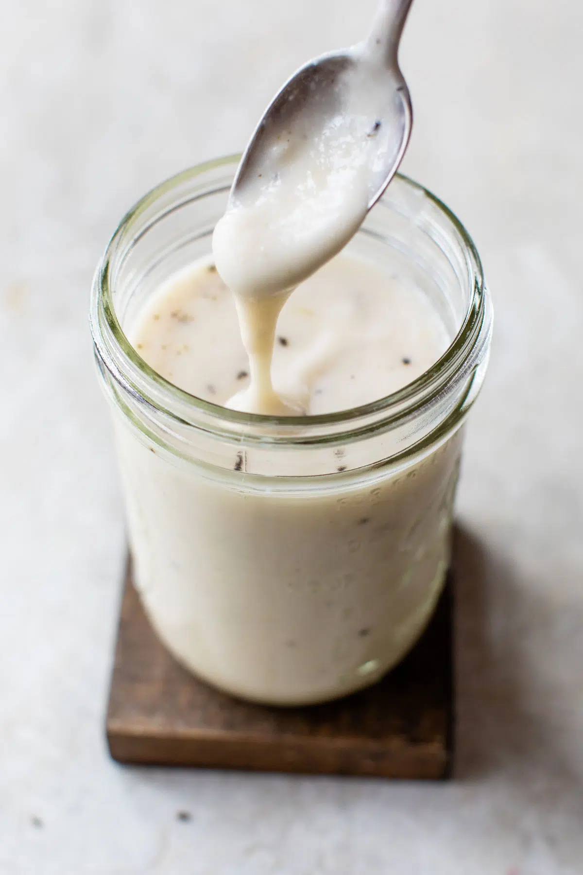 alfredo sauce in a glass jar with a spoon dipping in it