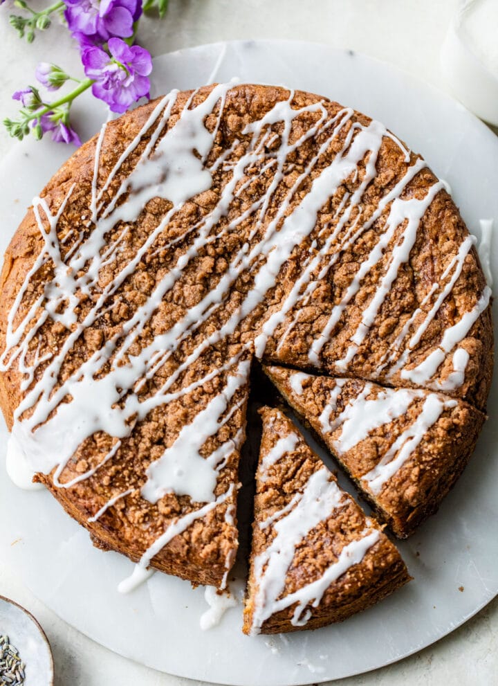 coffee cake on a round platter cut into slices and drizzled with a glaze