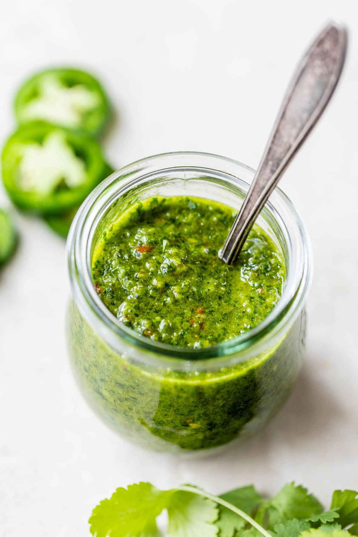 glass jar of spicy green sauce with a spoon in it