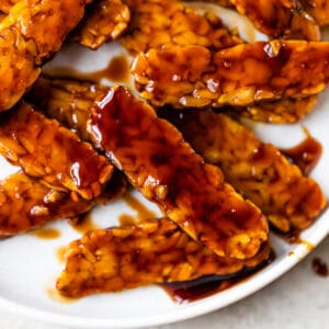 tempeh coated in an orange sauce on a plate