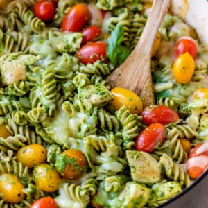 pesto pasta in a skillet with chicken and grape tomatoes