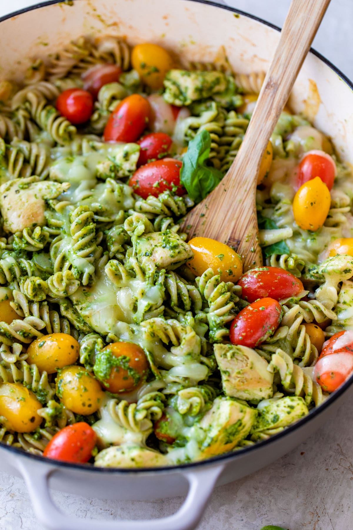 pesto pasta in a skillet with chicken and grape tomatoes