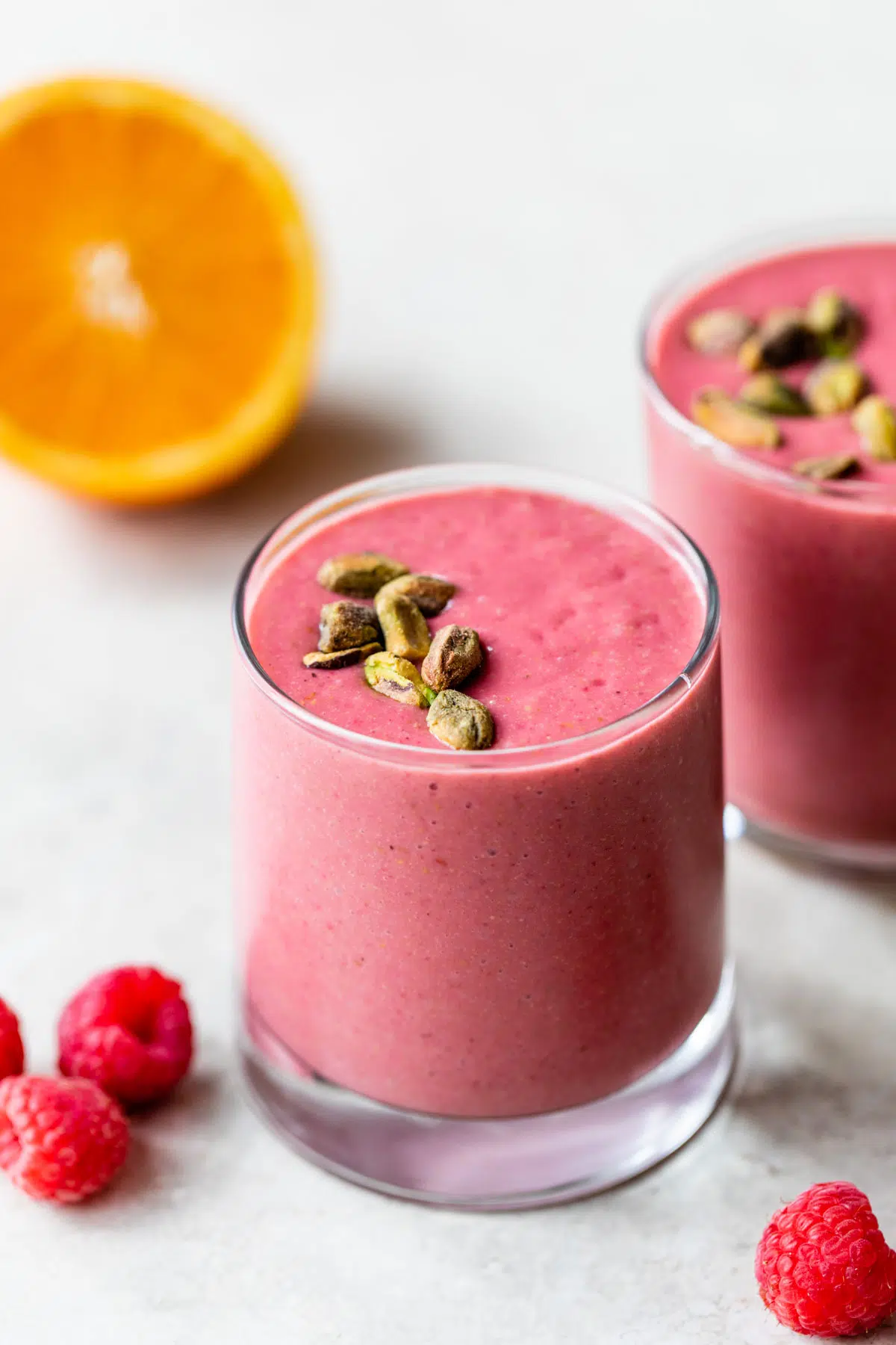 raspberry orange smoothie in a glass topped with pistachios