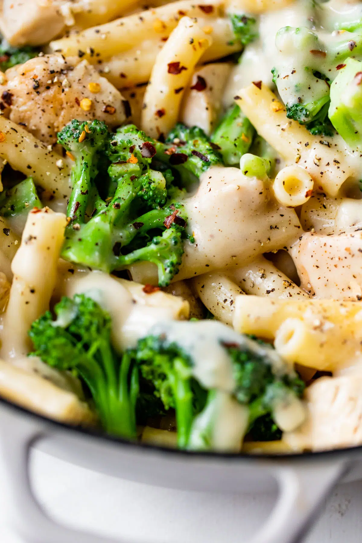 close up photo of chicken, pasta and broccoli in a skillet