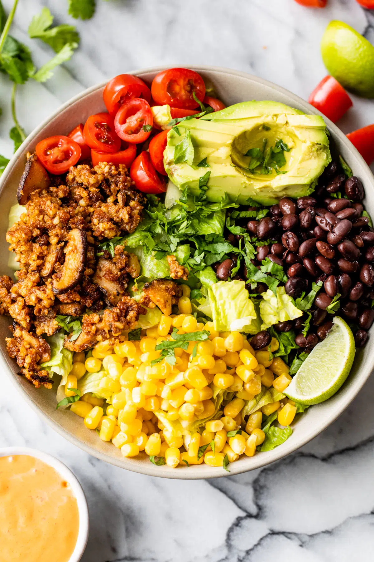 a bowl filled with corn, black beans, tomatoes, avocado, and walnut taco meat