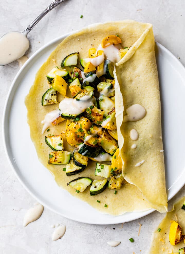 a crepe on a plate filled with zucchini and squash
