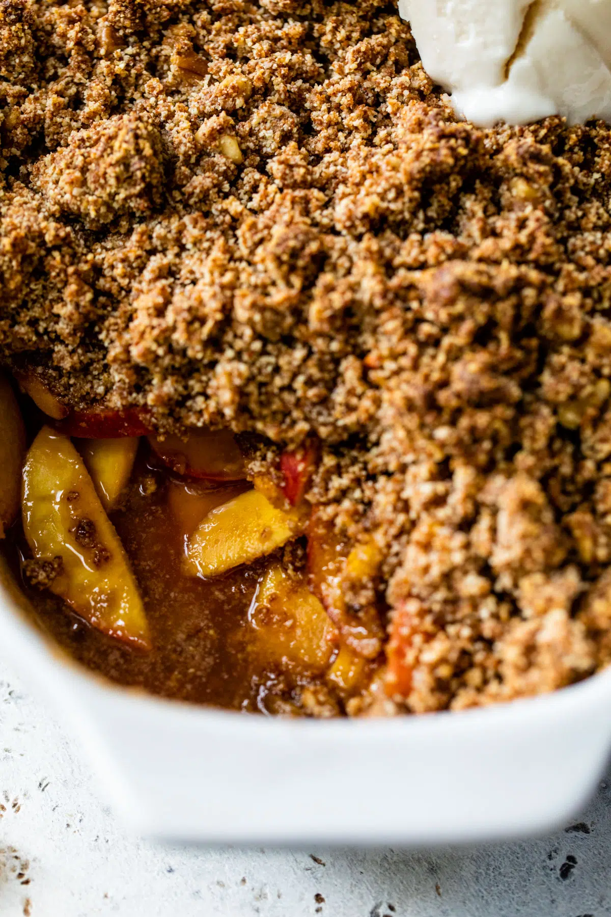 baked peaches in a dish topped with crumb topping