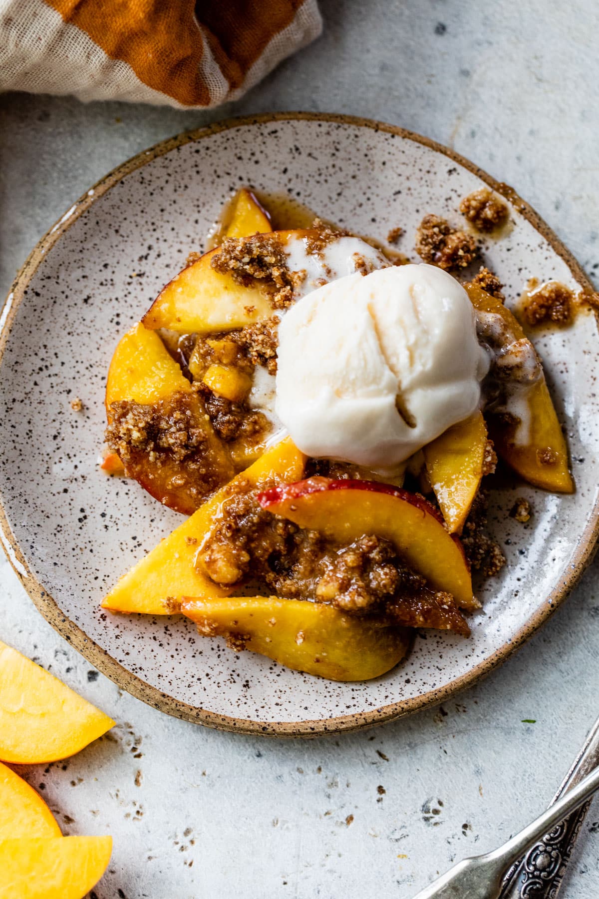 baked peaches on a plate topped with sugar and ice cream
