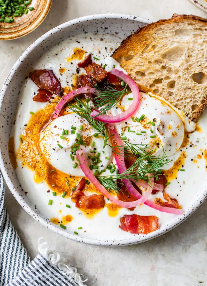 Greek yogurt topped with poached eggs, pickled red onion and bacon