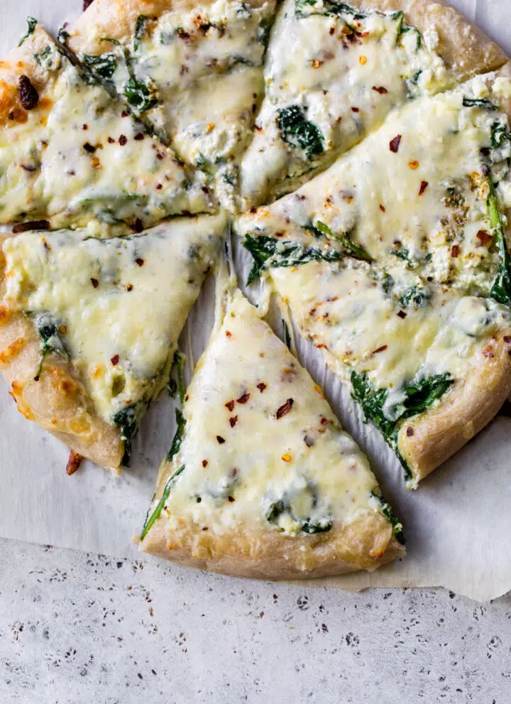 spinach and cheese pizza on parchment paper