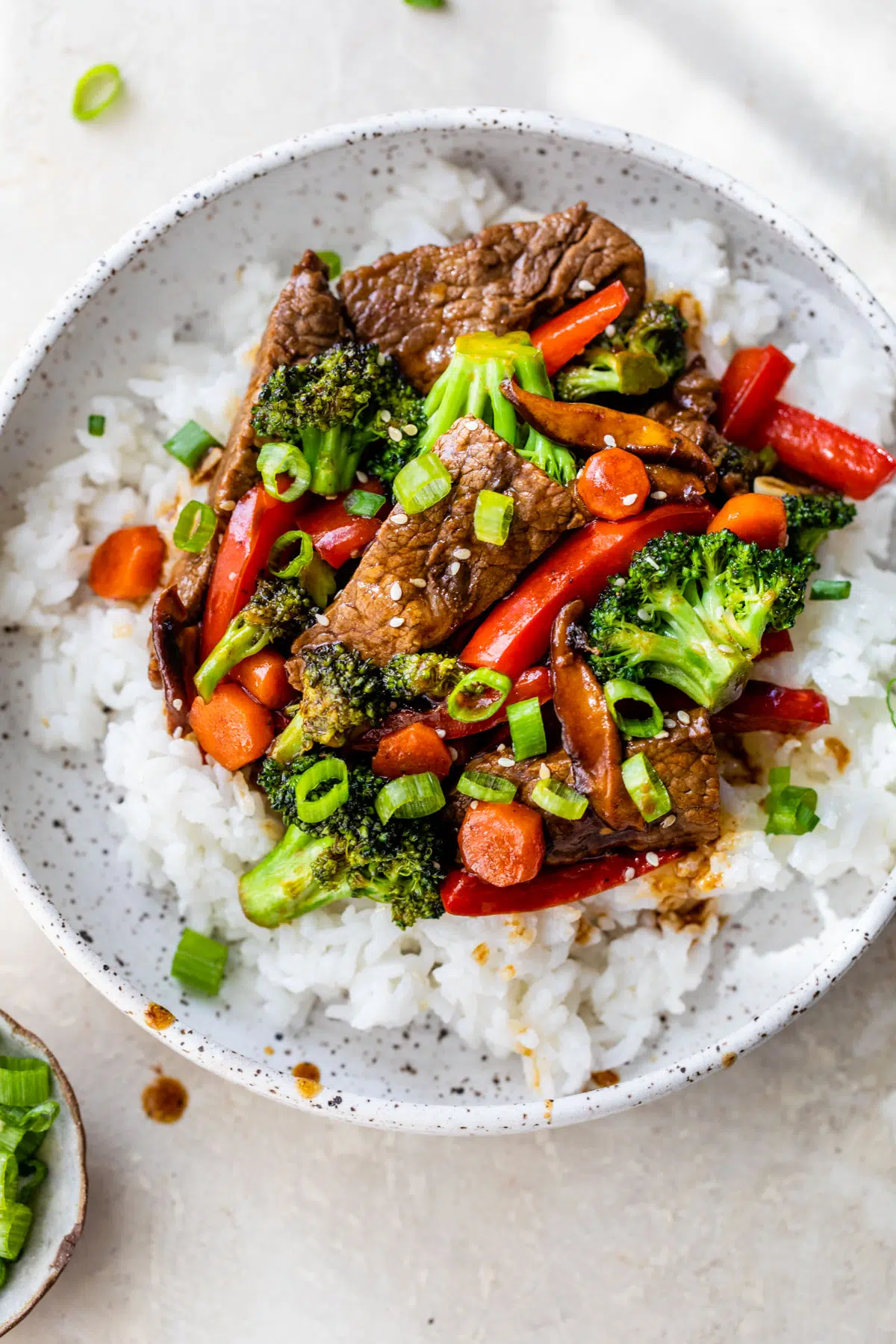 a bowl of rice topped with beef and vegetables like broccoli and carrots