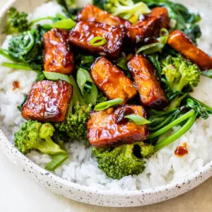 a bowl of rice topped with spinach, broccoli and marinated tofu