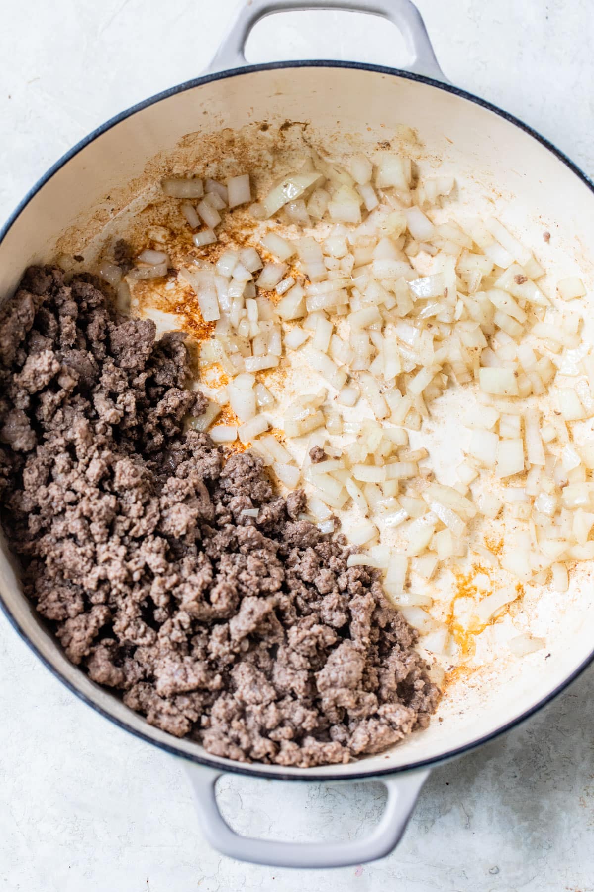 skillet with ground beef on one side and diced cooked onion on the other side
