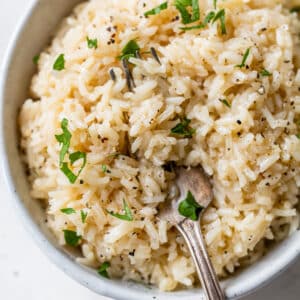 a bowl of rice with a fork topped with chopped parsley