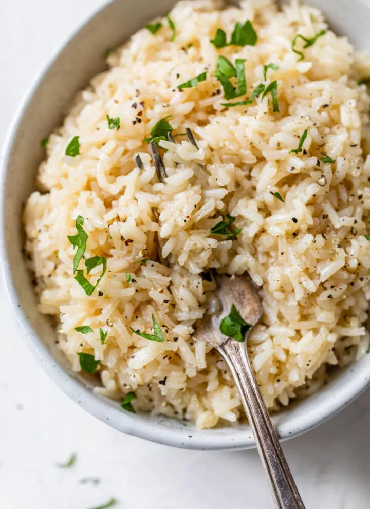 a bowl of rice with a fork topped with chopped parsley
