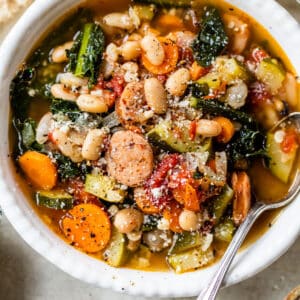 a bowl of soup with beans, sausage and kale