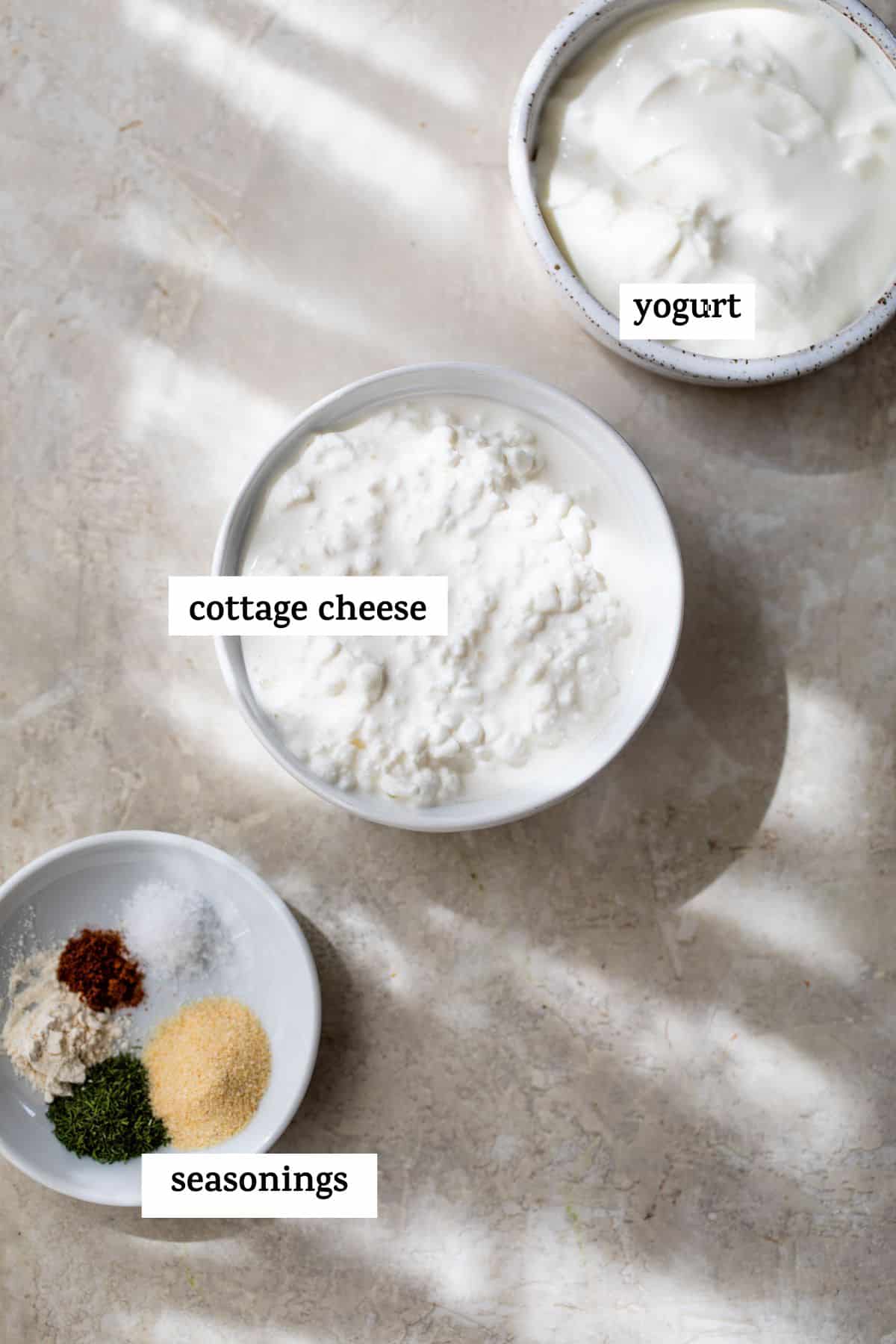 small bowl of yogurt, small bowl of cottage cheese and a small dish with seasonings on it