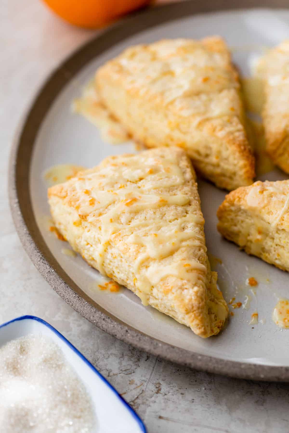 orange scones topped with glaze on a plate