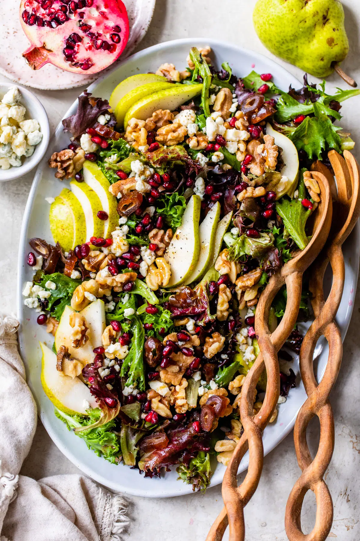 mixed greens on a platter topped with sliced pear, walnuts and pomegranate