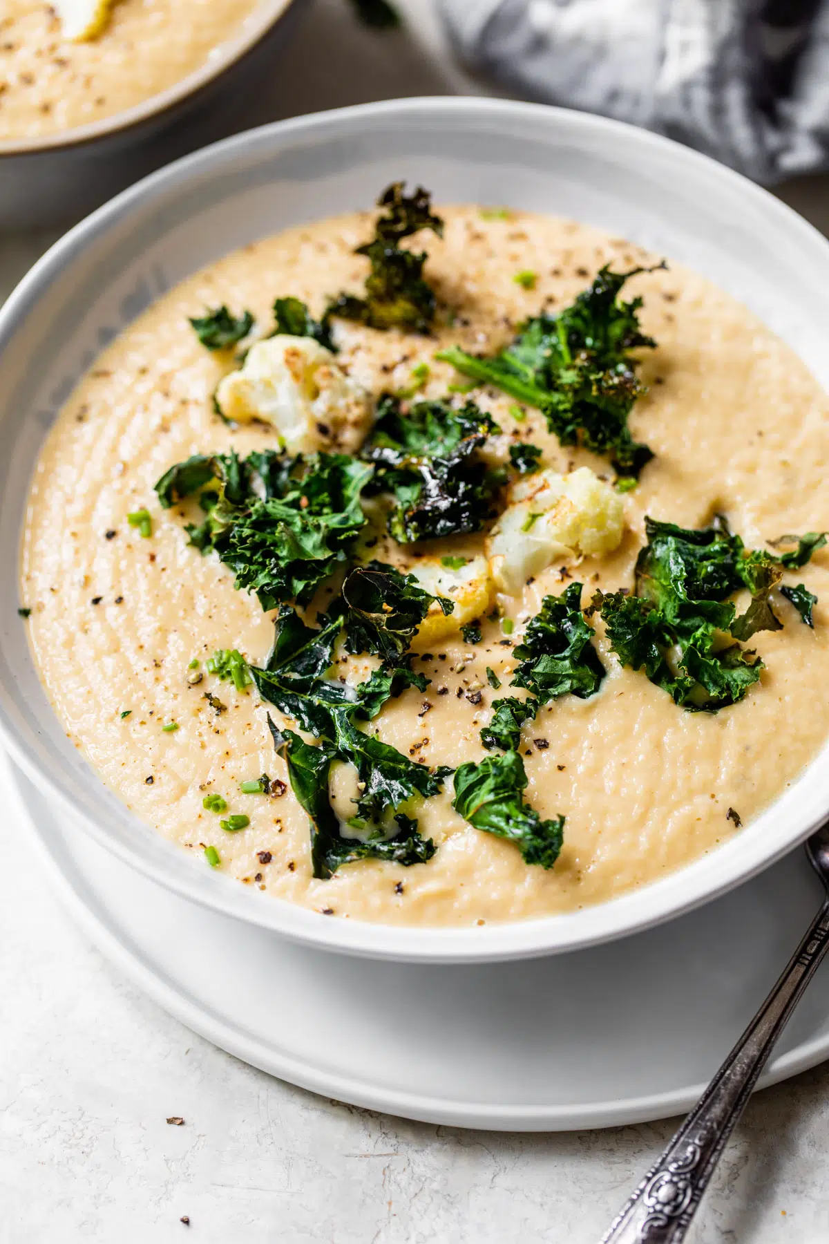 blended soup in a bowl topped with cauliflower florets and kale chips