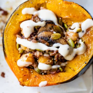 baked acorn squash stuffed with rice and drizzled with a white sauce