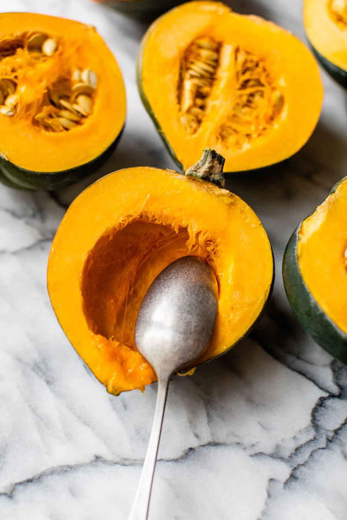 scraping seeds out of acorn squash with a spoon